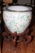 Large Oriental pottery fish bowl on wooden stand.