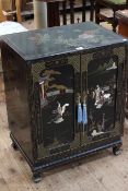 Oriental black lacquered two door cabinet with applied figure decoration, 72cm by 56cm.