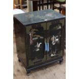 Oriental black lacquered two door cabinet with applied figure decoration, 72cm by 56cm.