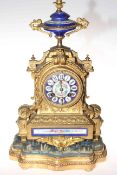 Gilt metal and enamel decorated mantel clock on gilt and upholstered base.