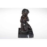 Bronze sculpture of praying child with clasped hands and kneeling on tasselled corner cushion, 21cm.
