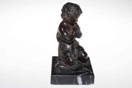 Bronze sculpture of praying child with clasped hands and kneeling on tasselled corner cushion, 21cm.