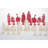 Intricately carved ivory chess set, red stained and plain, lacking one pawn.