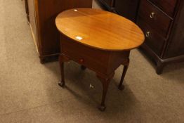 Oval mahogany sewing table on ball and claw legs.