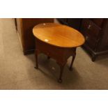 Oval mahogany sewing table on ball and claw legs.