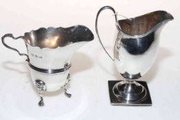 Two silver cream jugs, one helmet shaped and one on lion mask legs.