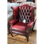 Deep buttoned ox blood leather wing armchair on cabriole legs.