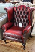 Deep buttoned ox blood leather wing armchair on cabriole legs.