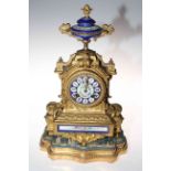 Gilt metal and enamel decorated mantel clock on gilt and upholstered base, total height 40cm.