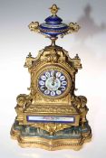 Gilt metal and enamel decorated mantel clock on gilt and upholstered base, total height 40cm.