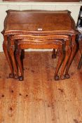 Burr walnut nest of three serpentine form tables on ball and claw legs (largest 56cm by 61cm).