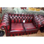 Ox blood buttoned leather two seater Chesterfield settee, 169cm long by 74cm high by 87cm deep.