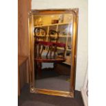 Rectangular wall mirror in gilt swept frame, 137cm by 75cm overall.