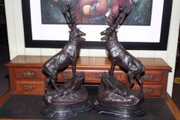 Large impressive pair of bronze stags standing on rocky outcrops raised on marble plinths.