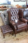 Brown deep buttoned leather wing back chair and footstool.