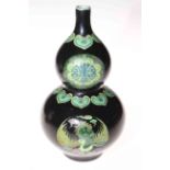 Chinese double gourd vase with panels of famille verte on black ground, 23cm.