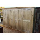 Large waxed pine four door cabinet fitted with shelves, 176cm by 284cm.