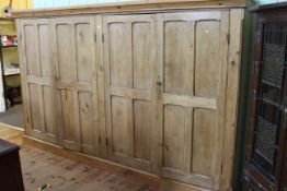 Large waxed pine four door cabinet fitted with shelves, 176cm by 284cm.