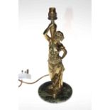 Ornate brass lamp modelled as a lady dressed in robes holding a jug, mounted on a stone plinth,