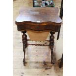 Victorian walnut fold top games table of serpentine form having frieze drawer above a tapering deep