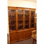 Yew wood finish breakfront bookcase with four astragal glazed doors above four cupboard doors.