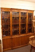 Yew wood finish breakfront bookcase with four astragal glazed doors above four cupboard doors.