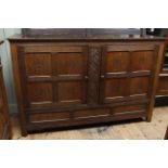 Oak plank top Arts & Crafts cupboard having two carved panel doors above a fall front door,