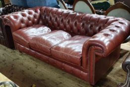 Deep buttoned red leather three seater Chesterfield settee.