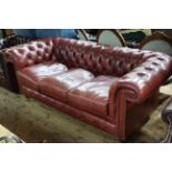 Deep buttoned red leather three seater Chesterfield settee.