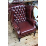 Thomas Lloyd deep buttoned ox blood leather wing armchair on cabriole legs.