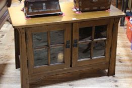 Sherry medium oak entertainment unit in Arts & Crafts style having two glazed panel doors,