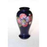 Moorcroft Pottery vase decorated with clematis on blue ground, 18cm high.