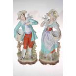 Pair of Continental bisque figures each carrying baskets and holding doves.