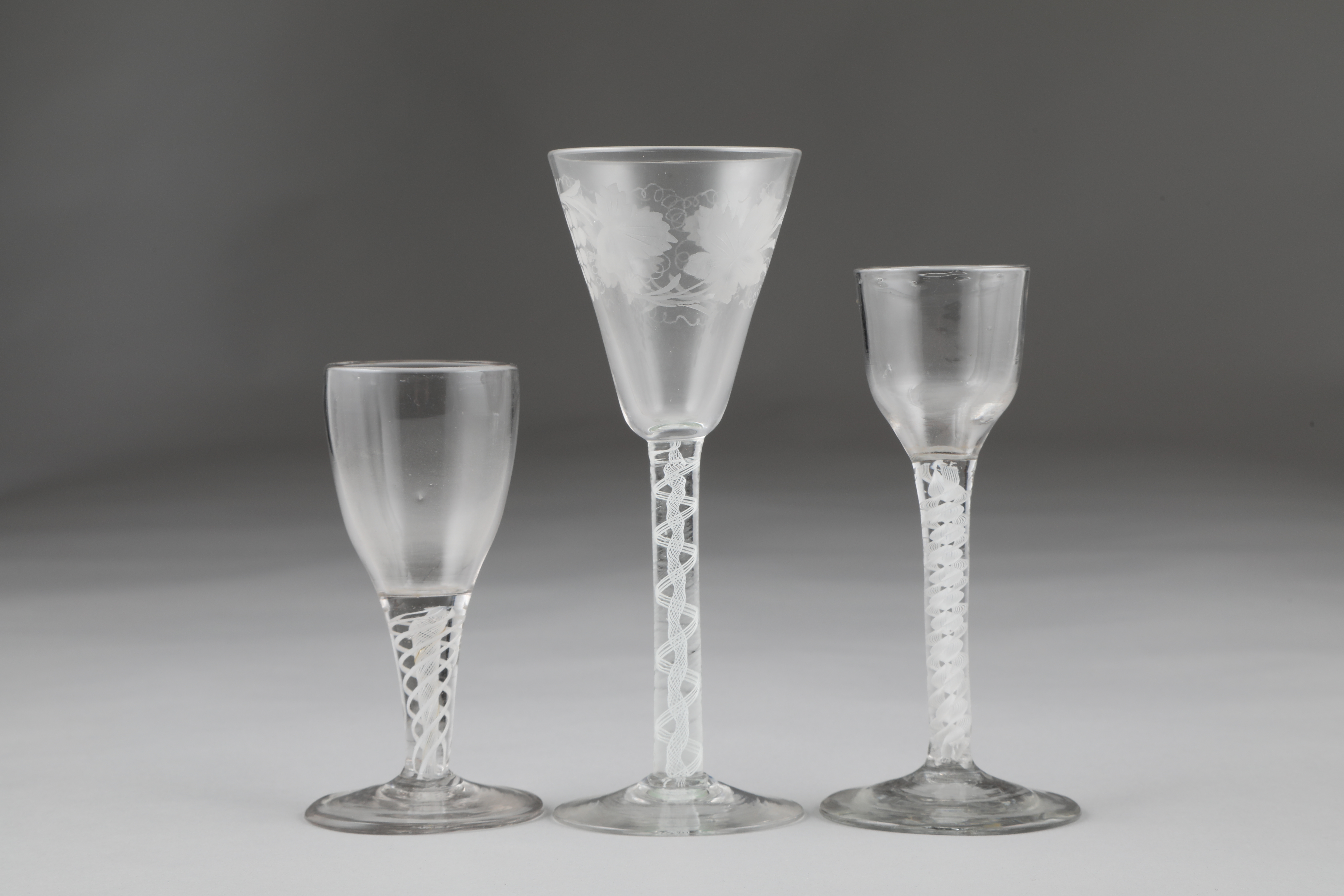 Three 18th century air twist stemmed glasses, the largest with bowl engraved with grapes and