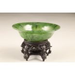Chinese green hardstone shallow bowl, exterior engraved with pond weed and fish, raised on a