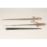 Two French bayonets, one with scabbard and one without, with wooden and brass grips.