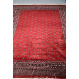 Large very fine Bokhara red ground carpet, geometric medallions with a stylised starburst border.