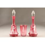 Pair of Mary Gregory cranberry glass decanters, one depicting a boy and the other a girl with