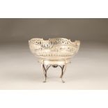 Pierced silver basket, circular form, raised on four cabriole legs united by crossed stretchers.