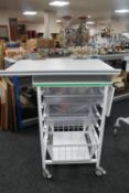 A metal medical trolley with two plastic trays and adjustable shelf and wire mesh basket