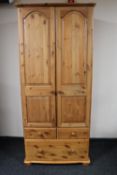 A pine double door wardrobe fitted with three drawers