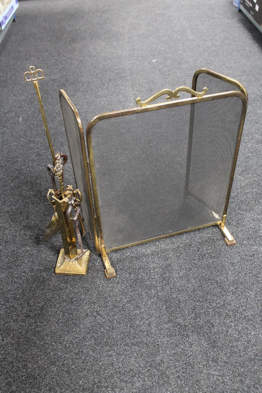 An antique brass three way folding fire screen together with a brass companion set