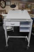 A metal medical trolley fitted with drawers with adjustable shelf