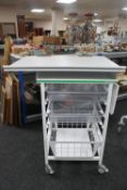 A metal medical trolley with two plastic trays and adjustable shelf and wire mesh basket