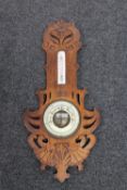 An Edwardian carved oak combination barometer thermometer