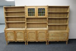 A three piece blond oak bookcase fitted with drawers