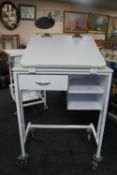 A metal medical trolley fitted with drawers with adjustable shelf