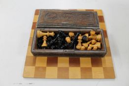 A wooden chess board and pieces in a carved hardwood eastern table box