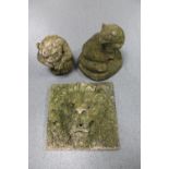 A weathered concrete lion mask plaque together with two garden figures of a gargoyle and a cat