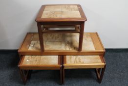 A nest of three teak tiled tables together with a tiled lamp table